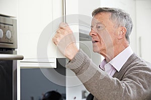 Forgetful Senior Man Looking In Cupboard