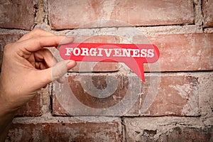 Forgiveness. Red speech bubble with text on a red brick background