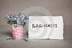 Forgiveness - text on white real paper with blue flowers