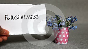 Forgiveness - word on gray background with blue flowers