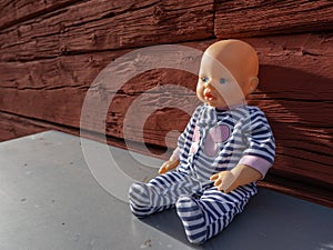 Forgotten doll in the background of red, old, wooden wall.