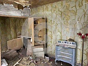 A forgotten hotel room with peeling wallpaper and plasterwork.