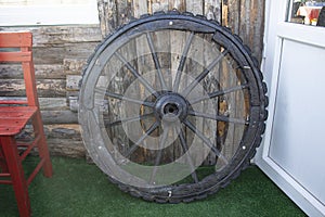 Forgotten old Wooden Wagon Wheel Leaning Against a wooden Wall. Cartwheels