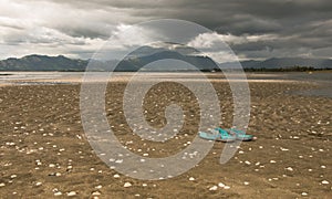 Forgotten slippers on a beach before a storm