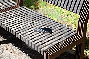 Forgotten smartphone on the wooden bench in the city park. lost phone in the park.