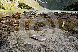 Forgotten white smartphone on a rock