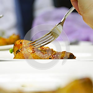 Fork in chicken leg on blurred background