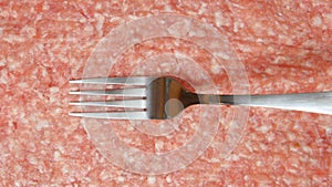 A fork in a cook hand is moving on a fresh forcemeat