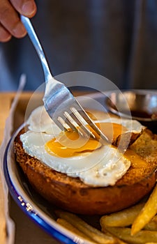 A fork cuts the egg yolk on a burger bun close-up