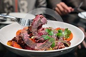 Fork dipping grilled beef sliced on dining table