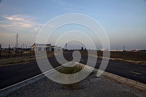 Fork in an empty road in an industrial complex at sunset