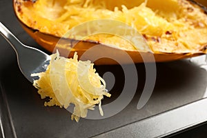 Fork with flesh of cooked spaghetti squash on blurred background