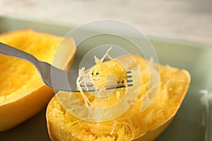 Fork with flesh over cooked spaghetti squash in baking dish