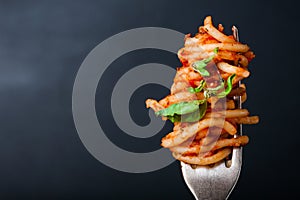 Fork full of twirled italian spaghetti with a bolognese meat sauce and basil.