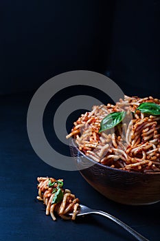 Fork full of twirled italian spaghetti with a bolognese meat sauce and basil.