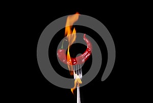 Fork impale to red hot chili on black background photo