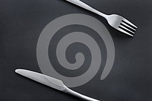 Fork and knife on black rough background