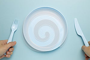Fork, knife and empty plate on sky blue background