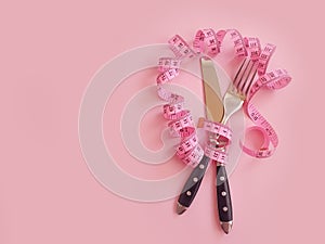 Fork knife measuring balance tape colored background overeating