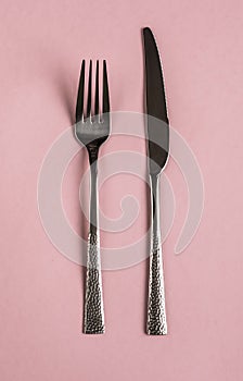 Fork and knife on a pink background, tools for food