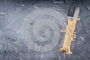 Fork with a knife in the sacking on a gray background