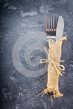 Fork with a knife in the sacking on a gray background