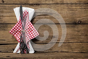 Fork and knife set with red white checked napkin on old rustic w photo