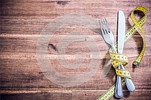 Fork And Knife Silverware Tied Together With Measuring Tape On A Table - Diet Concept