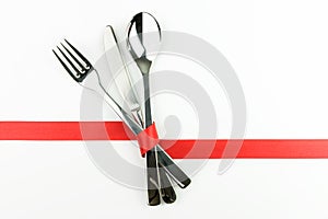 Fork, knife and spoon tied up with red ribbon