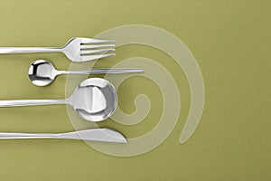 Fork, knife and spoons on green background, flat lay with space for text. Stylish cutlery set