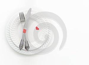 Fork, knife and two red hearts on white plate. Invitation for a romantic dinner, Valentine Day, love, dating concept
