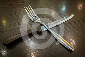 Fork and knife on wooden table.