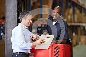 Fork Lift Truck Operator Talking To Manager In Warehouse
