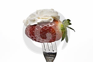 A fork and one strawberry with butterfat.