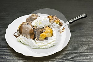 Fork with a portion of Profiterole with whipped cream.