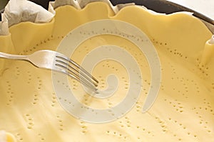 Fork pricking a dought in a baking tin with copy space for your text