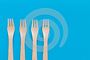 Fork setup Cutlery pattern on a bright blue background. Eco-friendly wooden disposable cutlery on bright backdrop. Wallpapers for