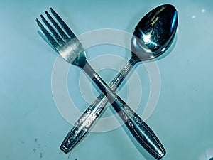 fork and spoon, arranged in an X shape.white background of paper. made of metal aluminum foil.