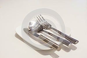 Fork, spoon and butter knife on a white plate