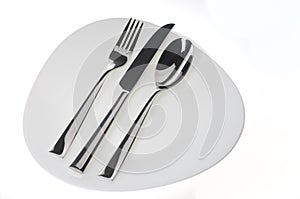 Fork, spoon and knife on a plate over white