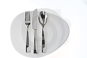 Fork, spoon and knife on a plate over white