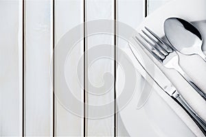 Fork, spoon and knife on plate on wooden