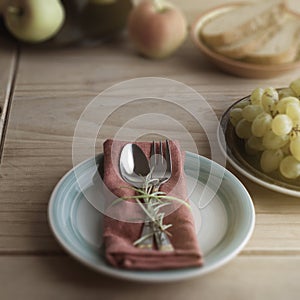 Fork and spoon over napkin, with a twig of rosemary. Rustic wooden background. Food education. Healthy food. Copy space.