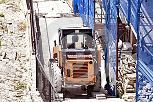 Forklift on a building site next to renovated house with scaffolding