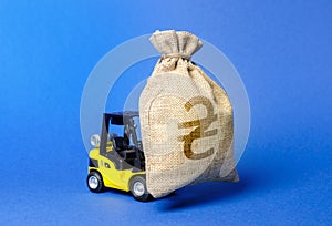 Forklift carries a huge money bag with the symbol of UA ukrainian hryvnia. Budget and taxpayer funds. Investment and capital photo