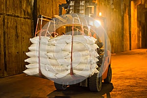 Forklift carries jumbo bag of refine white sugar to put on the stack inside warehouse. Sugar warehouse operations and management.