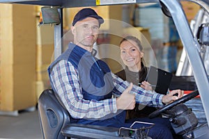 Forklift driver and female supervisor with clipboard at warehouse