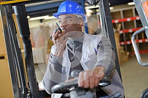 Forklift driver in industrial logistics warehouse looking at camera