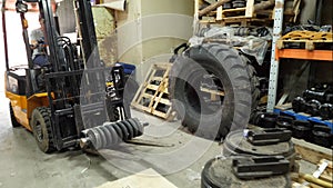 Forklift driver in protective vest driving forklift at warehouse of freight forwarding company. Man on the forklift