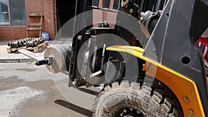 Forklift driver in protective vest driving forklift at warehouse of freight forwarding company. Man on the forklift